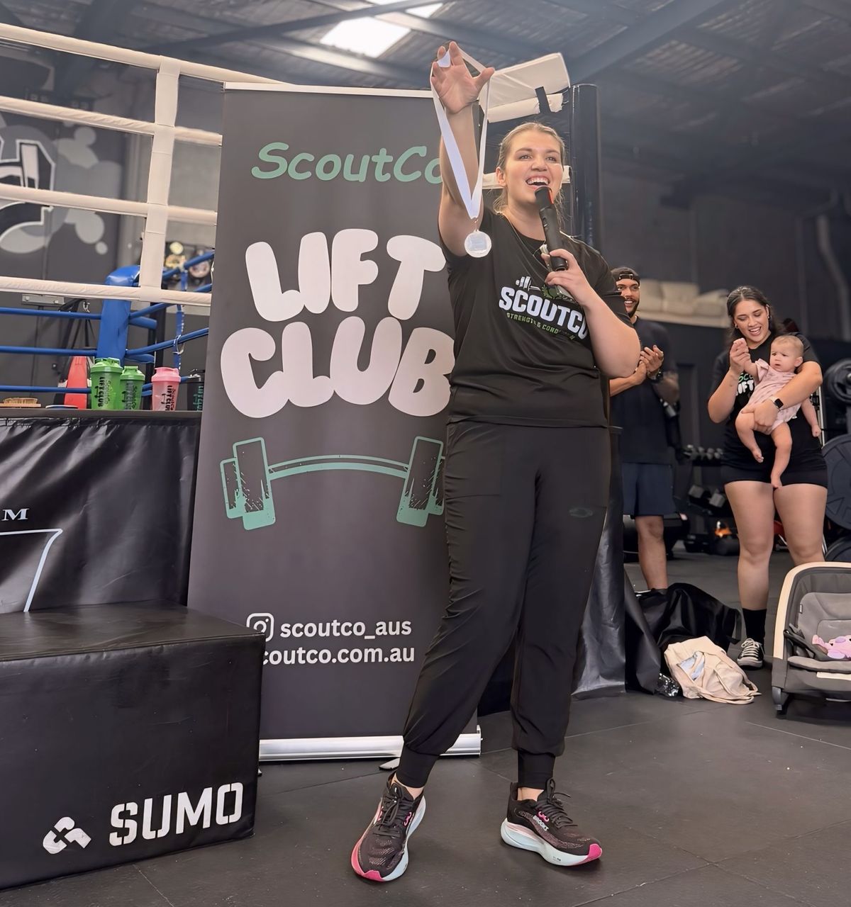 Coach Kirst presenting a medal at a ScoutCo Lift Club competition